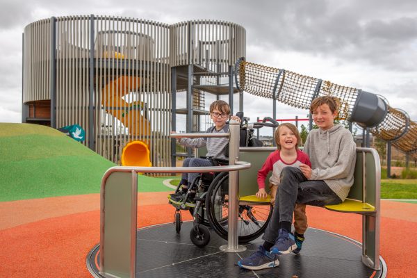 Two children sitting on bench and one in wheelchair