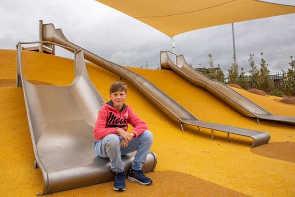 A boy sitting on edge of slide