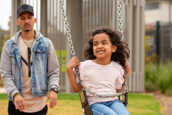 A child on the swing with a parent accompanying them