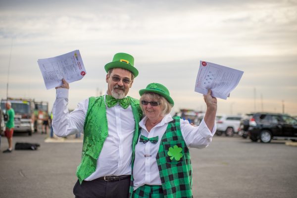 A couple holding paper in the air dressed in green festive costumes