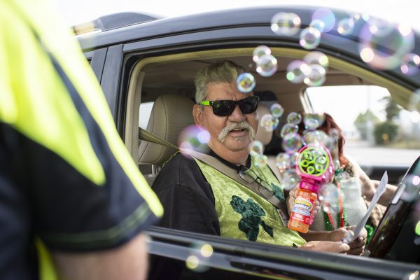 Man in car blowing bubbles at camera