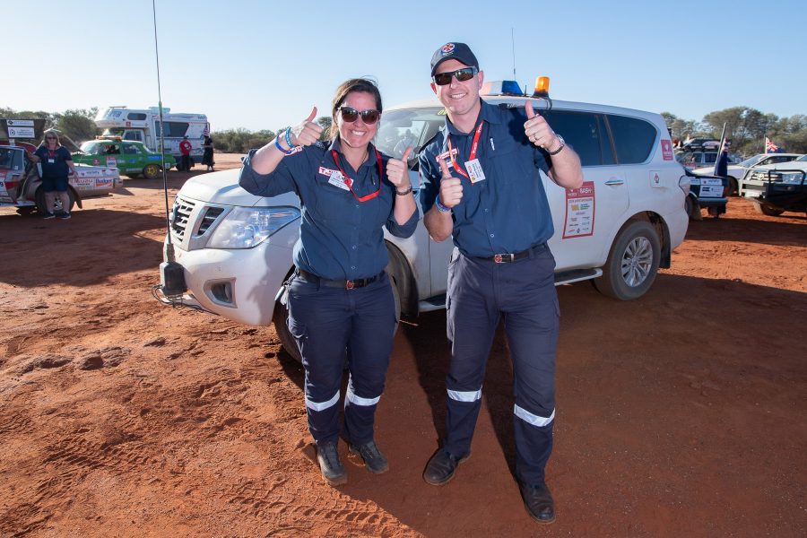Two paramedics standing infront of a white 4WD with their thumbs up