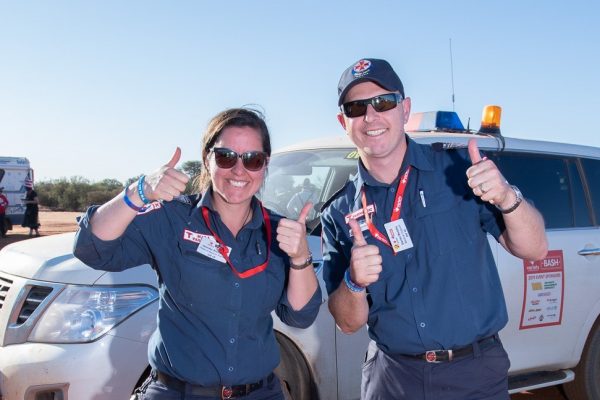 Two paramedics standing infront of a white 4WD with their thumbs up